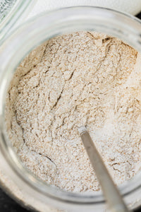Whole grain baking mix in a glass jar with a spoon