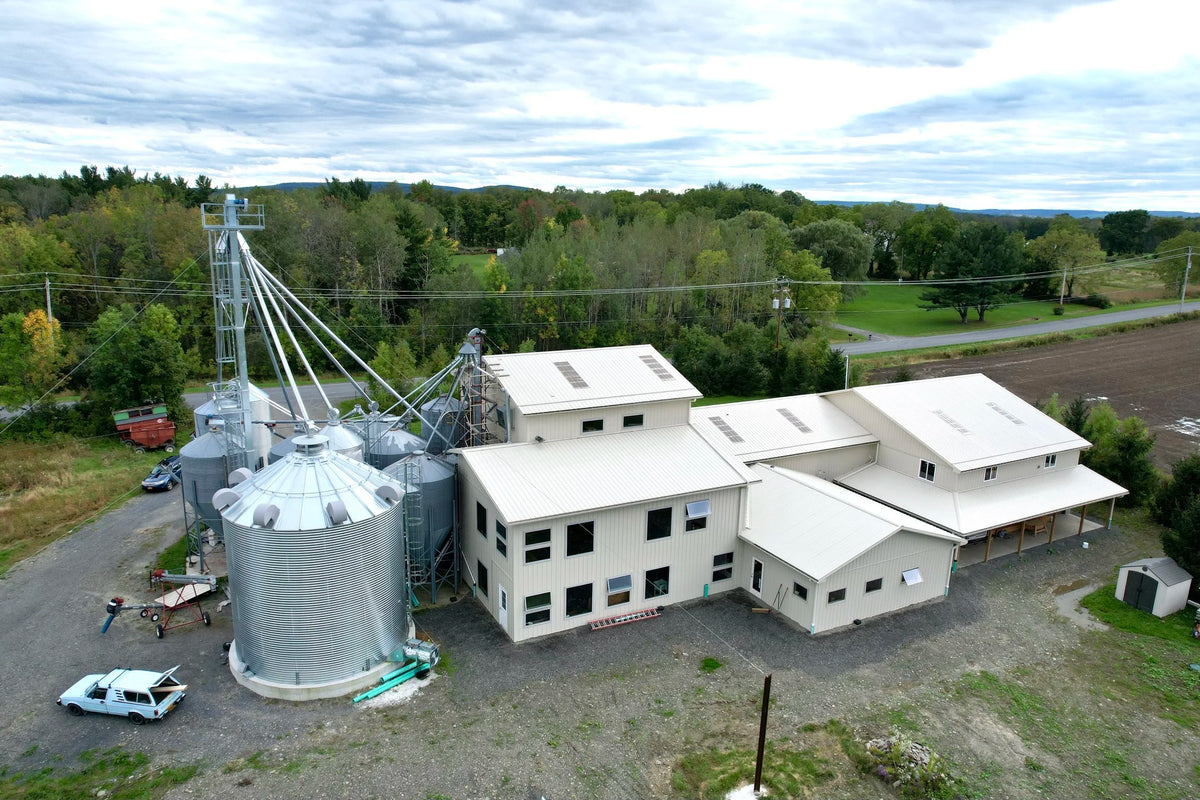 Aerial view of the Farmer Ground Flour mill in Trumansburg, New York, with silos, grain storage, and surrounding fields. Photo by Dave Katz.